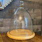 Tall glass dome with round wood serving board