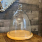 Tall glass dome with round wood serving board